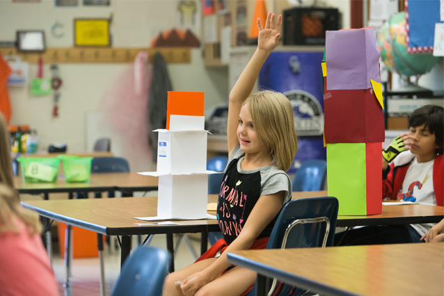 PHoto of Child in Classroom Raising her Hand