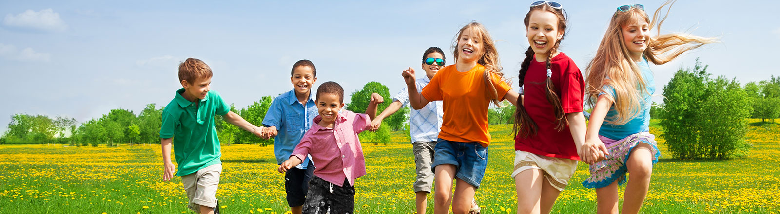 Group of kids running through a field on a sunny day