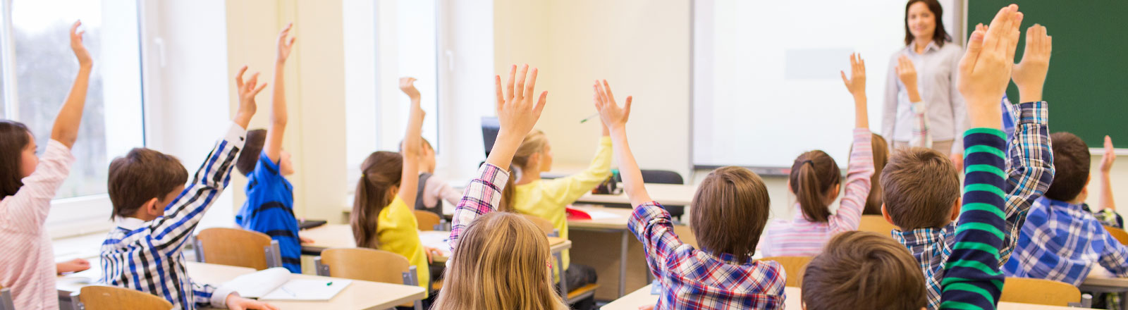 Elementary students raising hand in front of teacher