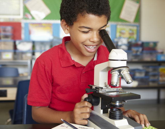 Elementary student in science class looking into microscope
