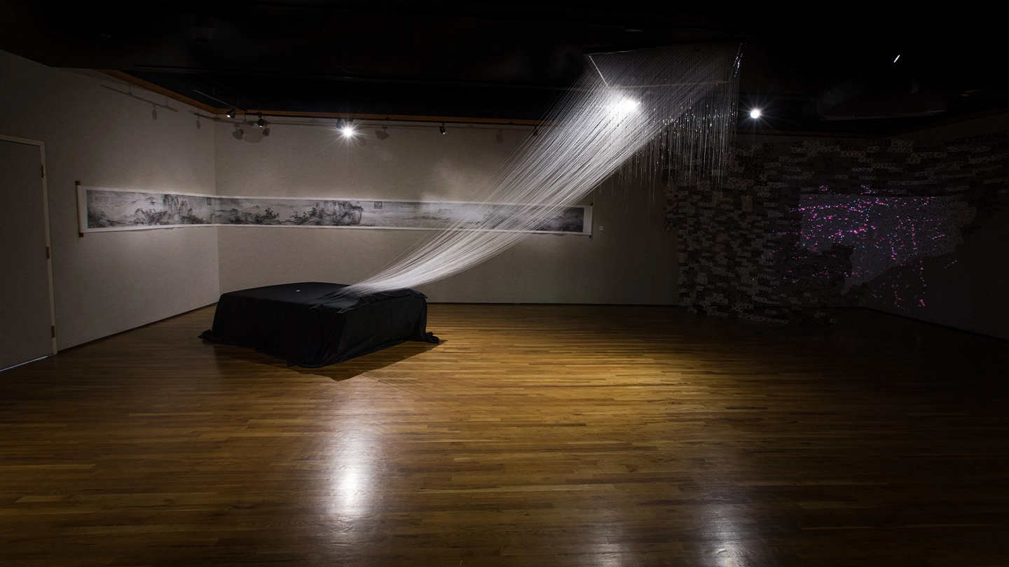 Art exhibit with low lighting and a hanging art installation.