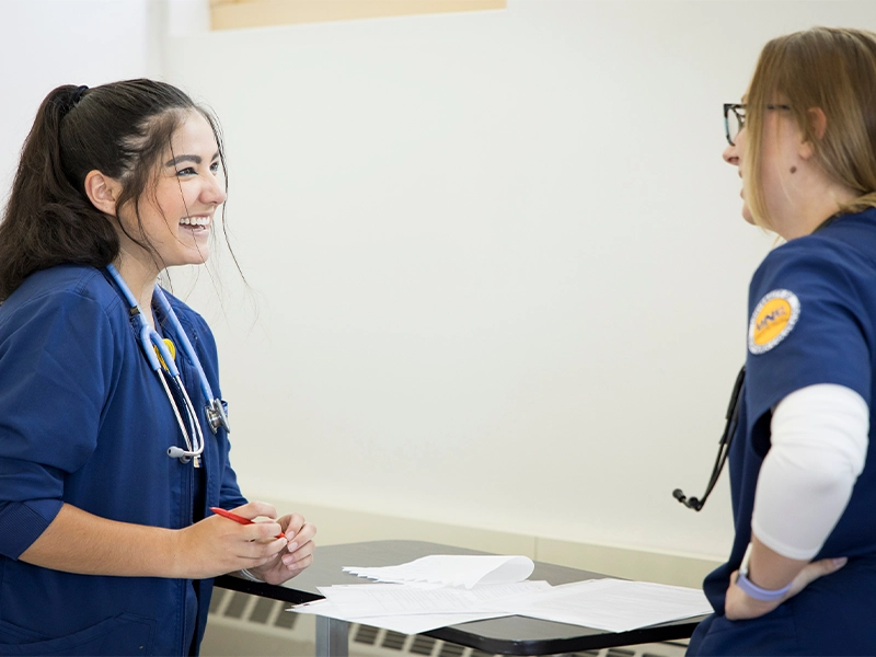 A UNC BSN nursing student talking with a nurse coworker.