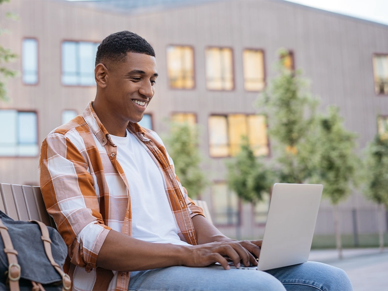 Psychology bachelor's degree completion student sitting outside doing coursework online.