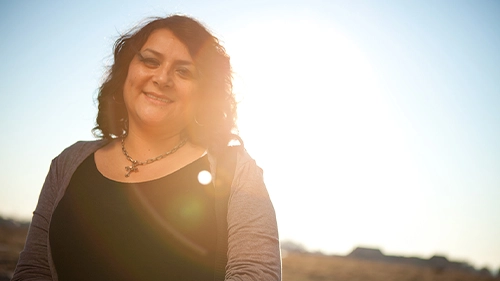 Gena Duran, UNC graduate, standing in a field in Colorado.
