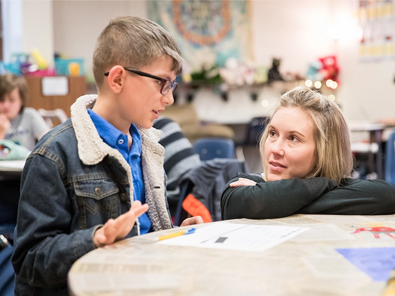 Elementary education bachelor's degree completion teacher listening to student in the classroom.