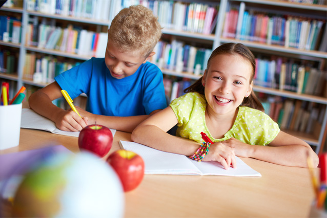 Photo of Children smiling at a school desk