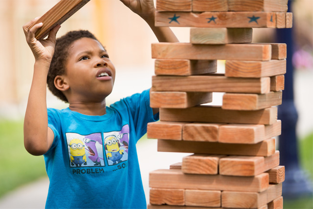 Photo of Child building Giant Jenga tower