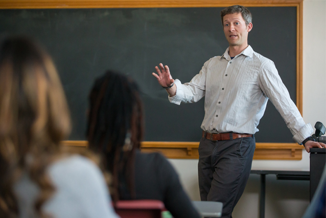 Teacher talking to students in front of a chalkboard